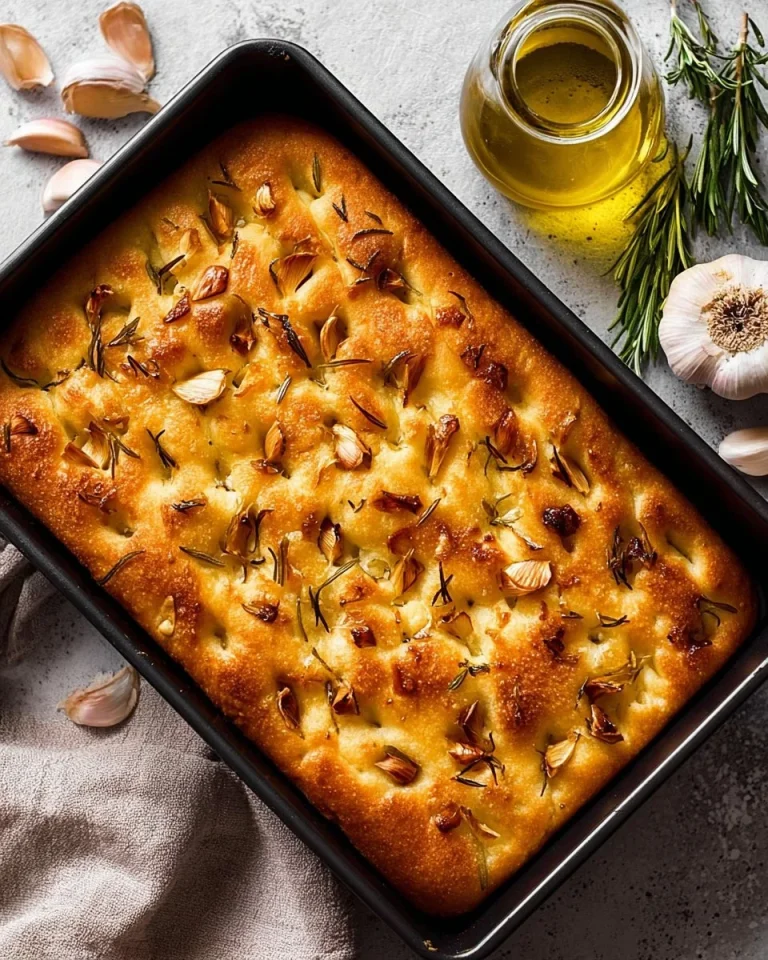 Homemade focaccia bread fresh out of the oven, golden and topped with herbs.