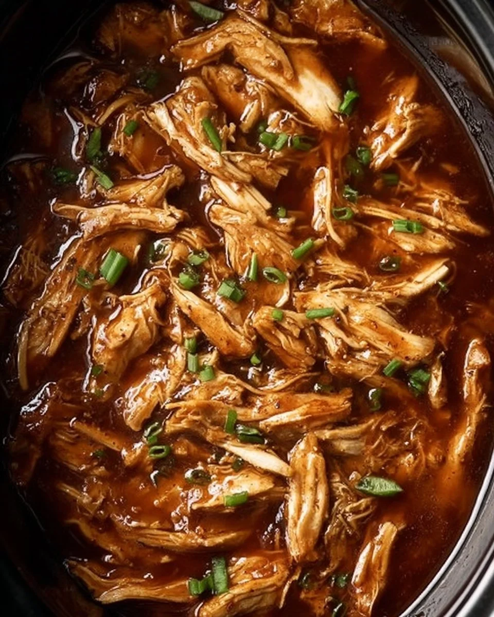 Crock Pot Bourbon Chicken served with rice and garnished with green onions.