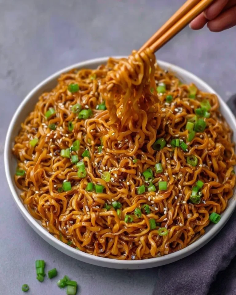 Bowl of easy saucy ramen noodles topped with fresh vegetables and herbs