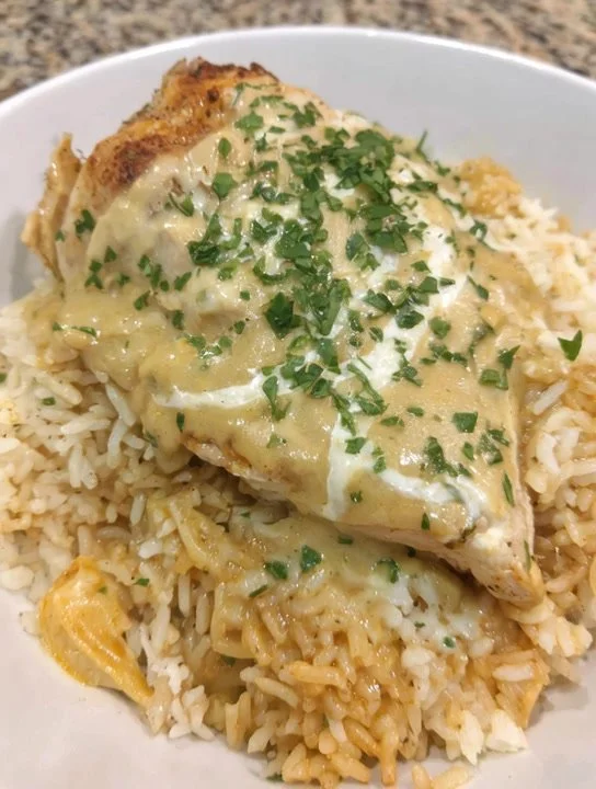 Delicious plate of rice with savory cheesy chicken on top.