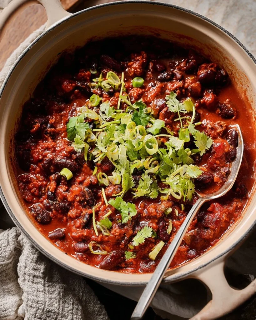 A bowl of hearty vegan chili topped with fresh herbs and avocado.