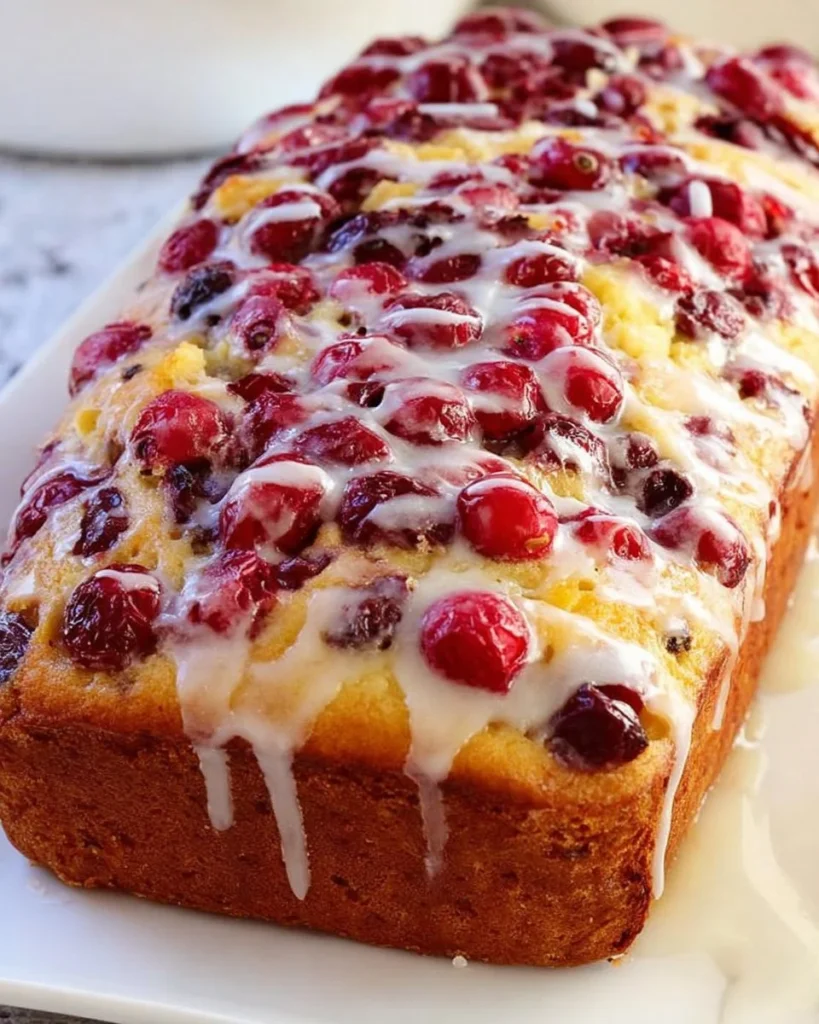 Freshly baked cranberry orange bread with slices on a wooden board