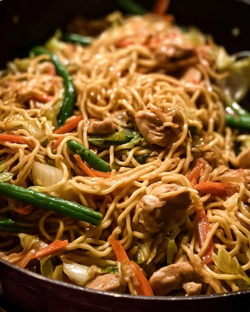 Plate of flavorful fried noodles garnished with vegetables and spices