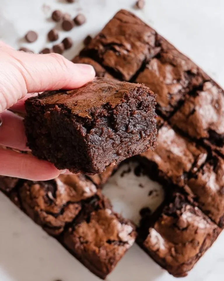 Decadent fudgy brownies topped with chocolate and nuts on a wooden table