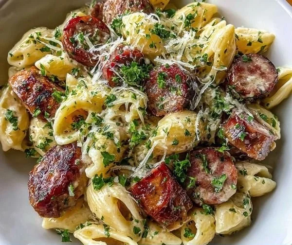 Garlic butter sausage bites served with creamy parmesan pasta in a bowl.