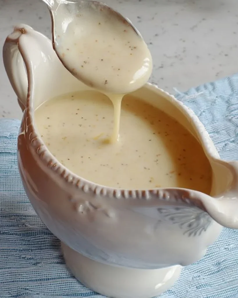 Homemade white country gravy served over biscuits in a bowl