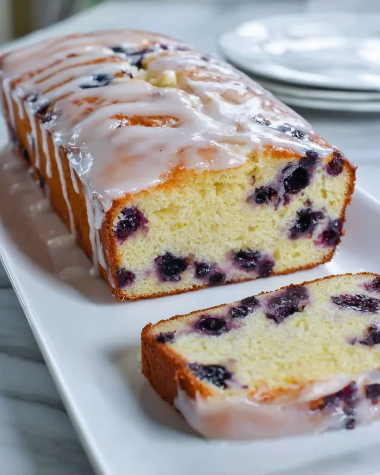 A slice of lemon blueberry cake topped with blueberries and lemon zest
