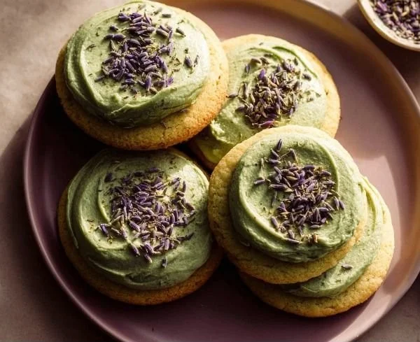 Delicious matcha sugar cookies topped with lavender frosting on a plate.