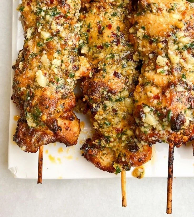 Ranch garlic parmesan chicken skewers ready to be grilled, garnished with herbs.