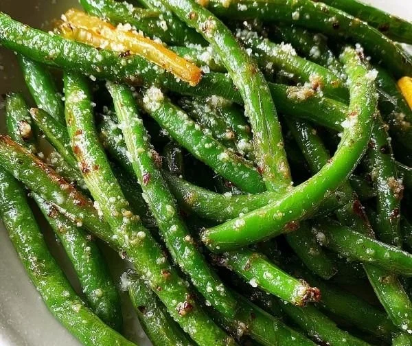 Plate of roasted Parmesan green beans garnished with herbs