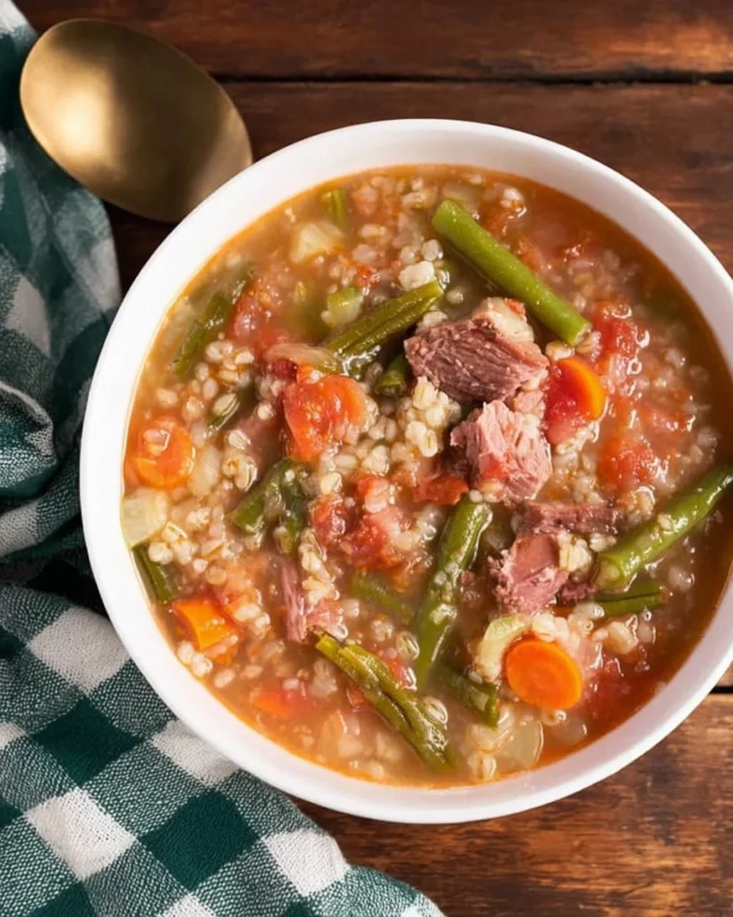 Bowl of slow cooker ham vegetable barley soup garnished with fresh herbs.