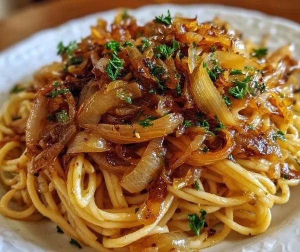 Vegan caramelized onion pasta topped with fresh herbs and served in a bowl