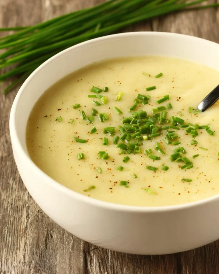 Bowl of vegan potato leek soup garnished with fresh herbs