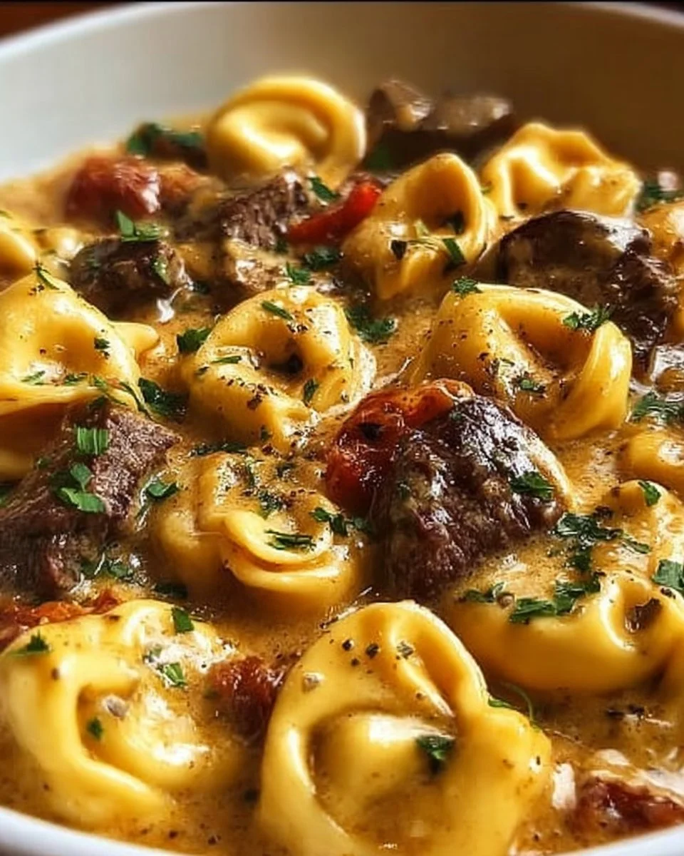 Cheesesteak tortellini in rich provolone sauce served on a plate