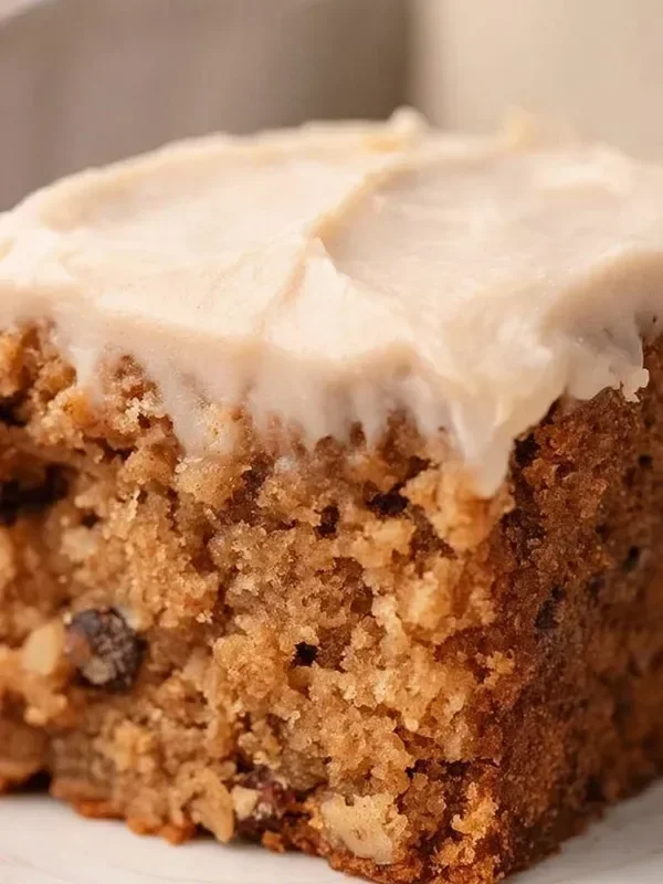 Delicious homemade Applesauce Cake topped with cream and served on a plate.