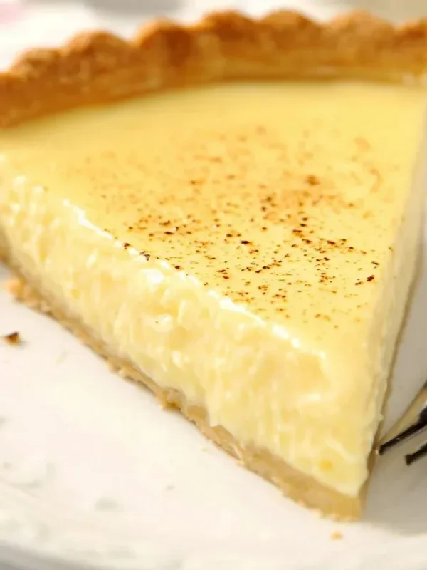 Delicious homemade custard pie slice on a plate with fresh fruit