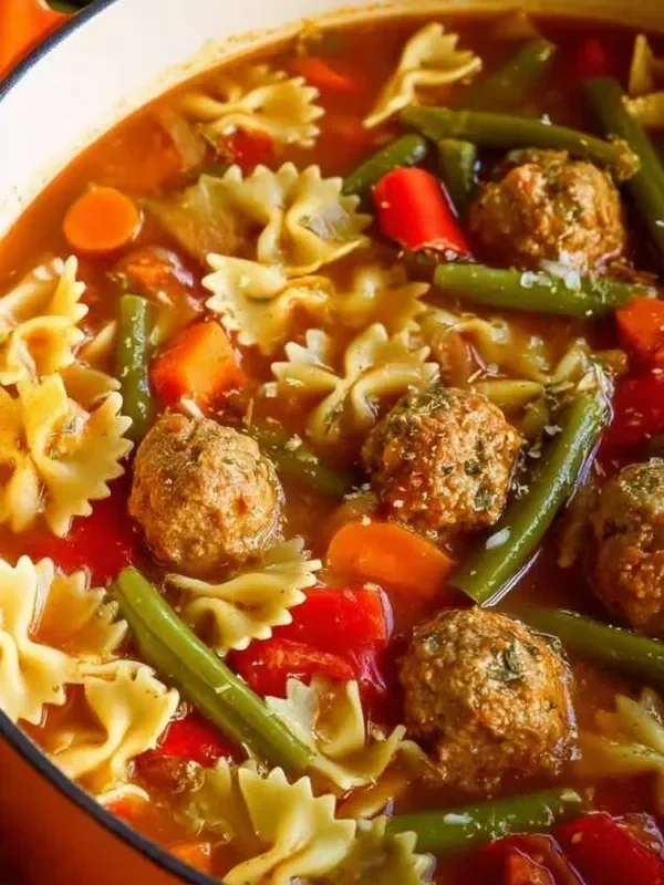 A comforting bowl of meatball soup with fresh herbs and vibrant vegetables
