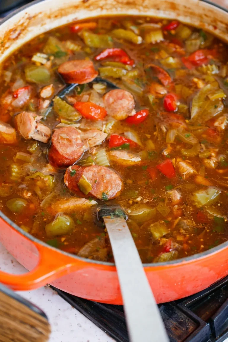 Authentic Louisiana Style Chicken and Sausage Gumbo Made with Spicy Andouille Sausage, Onions, Celery, and Bell Pepper, Commonly Referred to as the Holy Trinity, and Okra. Bowl of authentic Louisiana chicken and sausage gumbo with Andouille sausage and vegetables.