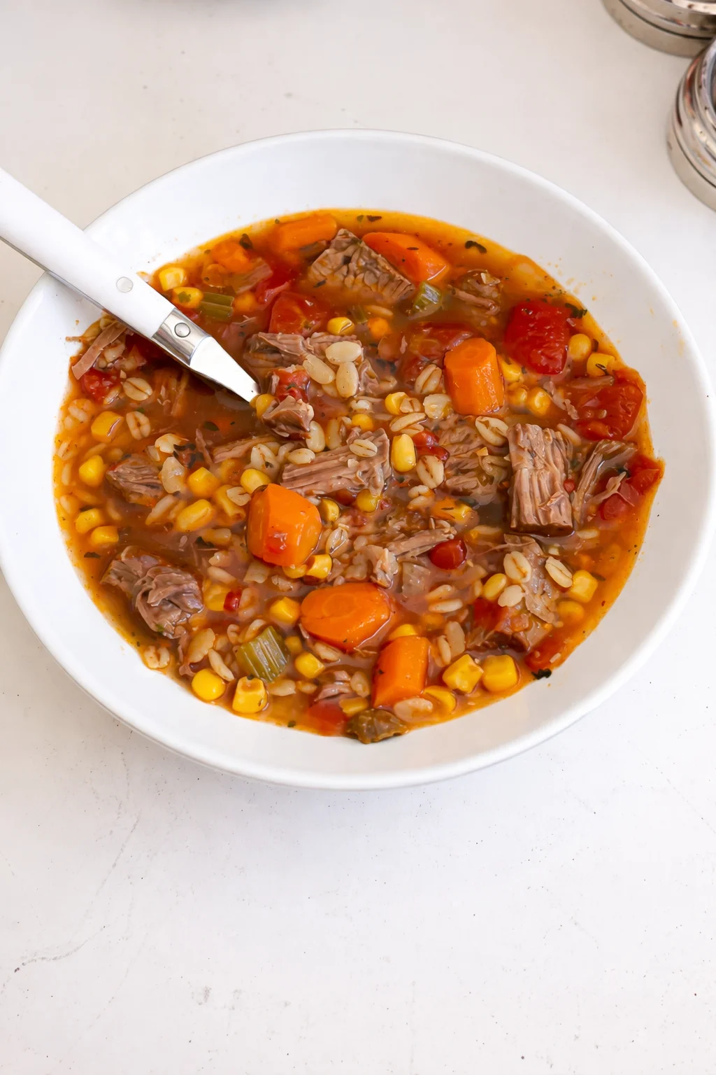 A warm bowl of beef barley soup with chunks of beef and vegetables in broth.