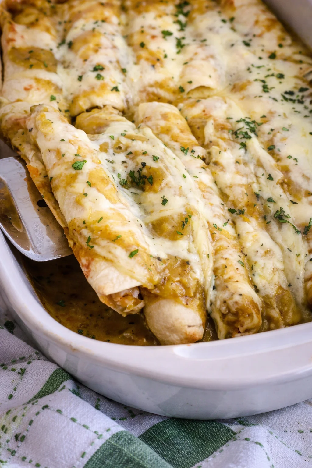 Cheesy chicken enchiladas topped with melted cheese in a baking dish