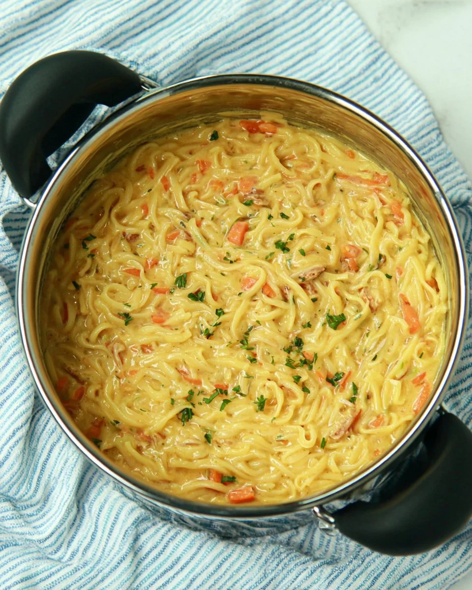 A bowl of creamy Crack Chicken Noodle Soup garnished with herbs.