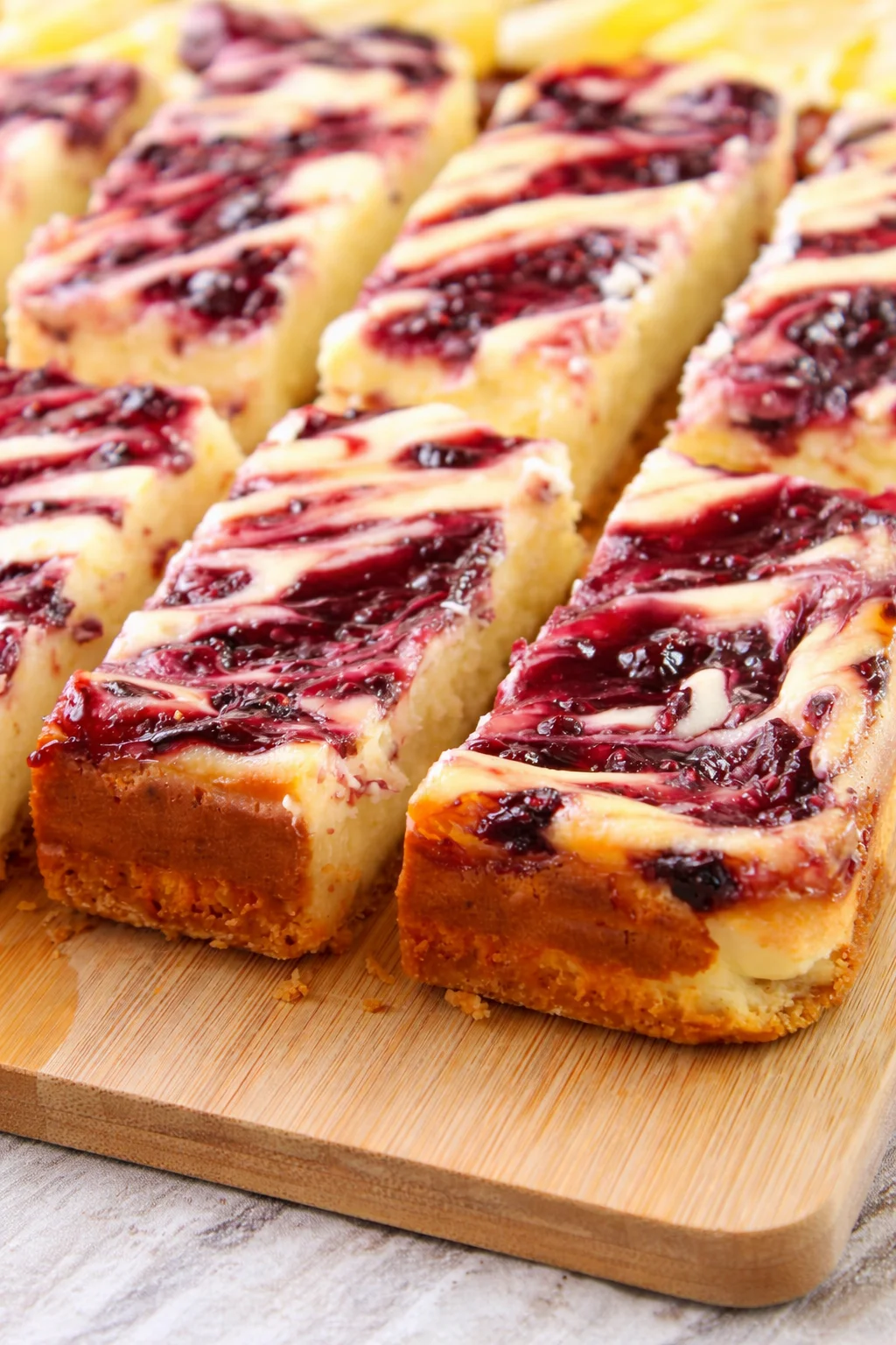 Lemon raspberry cheesecake bars on a white plate, topped with fresh raspberries