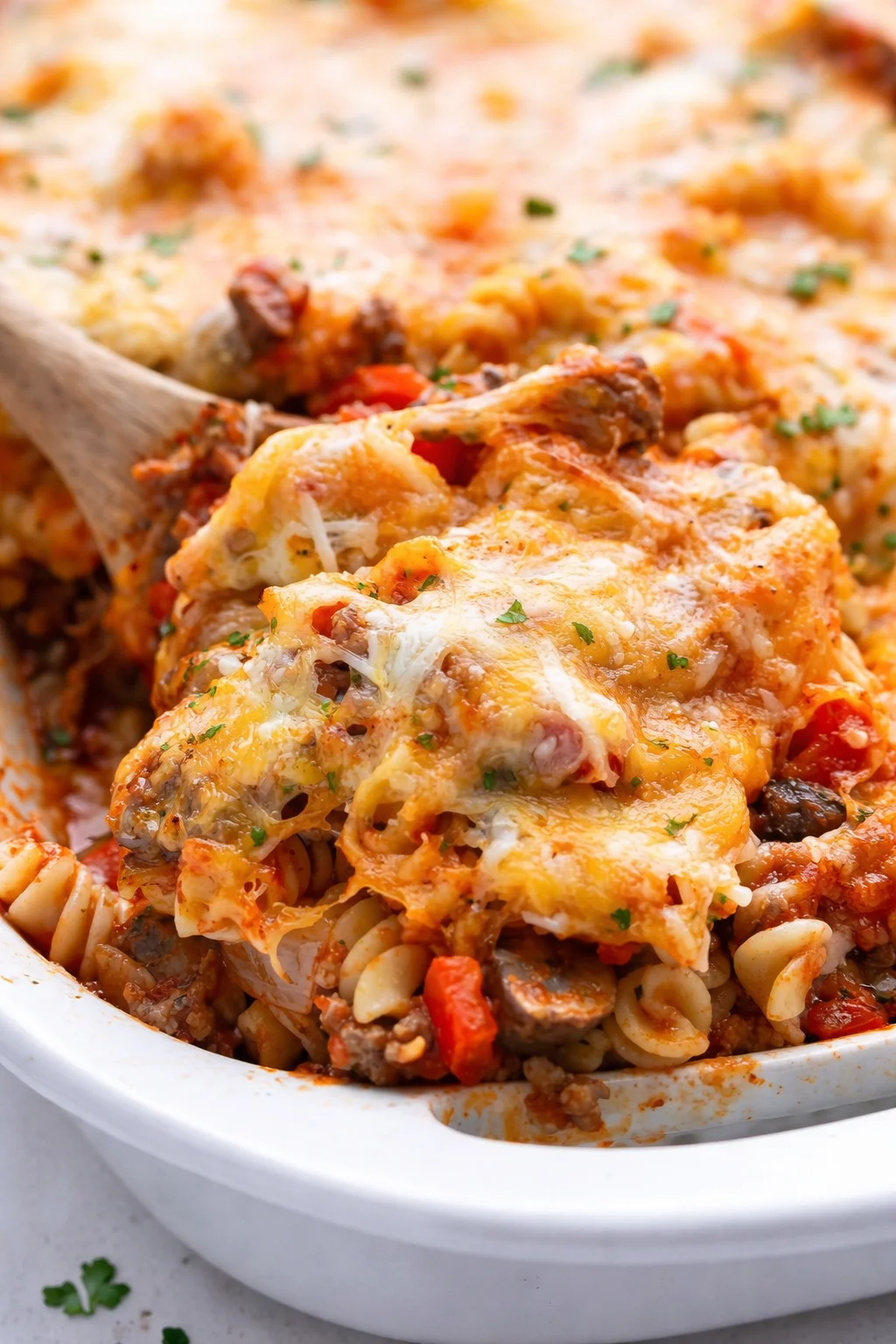 New on the blog! Johnny Marzetti Casserole features ground beef, sausage, mushrooms, onions, and bell peppers, in tomato sauce, all smothered with cheddar and mozzarella cheese. Delicious Johnny Marzetti Casserole with beef, sausage, cheese, and vegetables