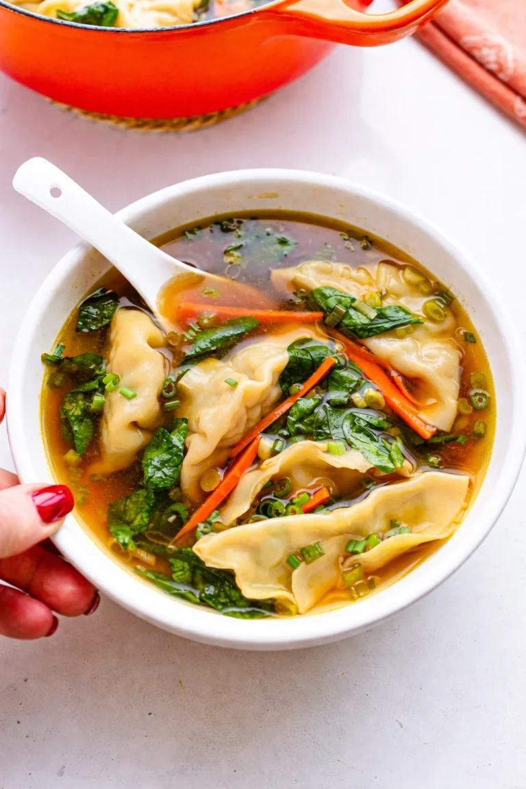 Delicious dumpling soup with carrots, spinach, potstickers, garlic, and ginger.