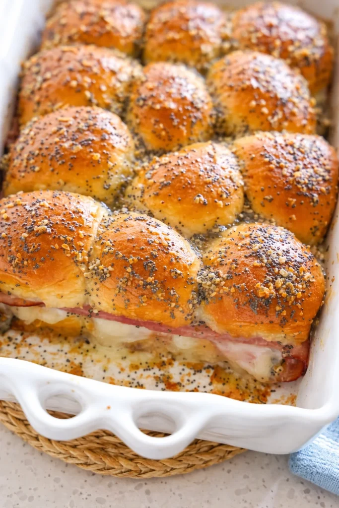 Party-worthy and delectable Ham and Cheese Sliders recipe made with Hawaiian Sweet Rolls, smoked honey ham, and Swiss Cheese slathered with a Dijon mustard poppy seed butter.