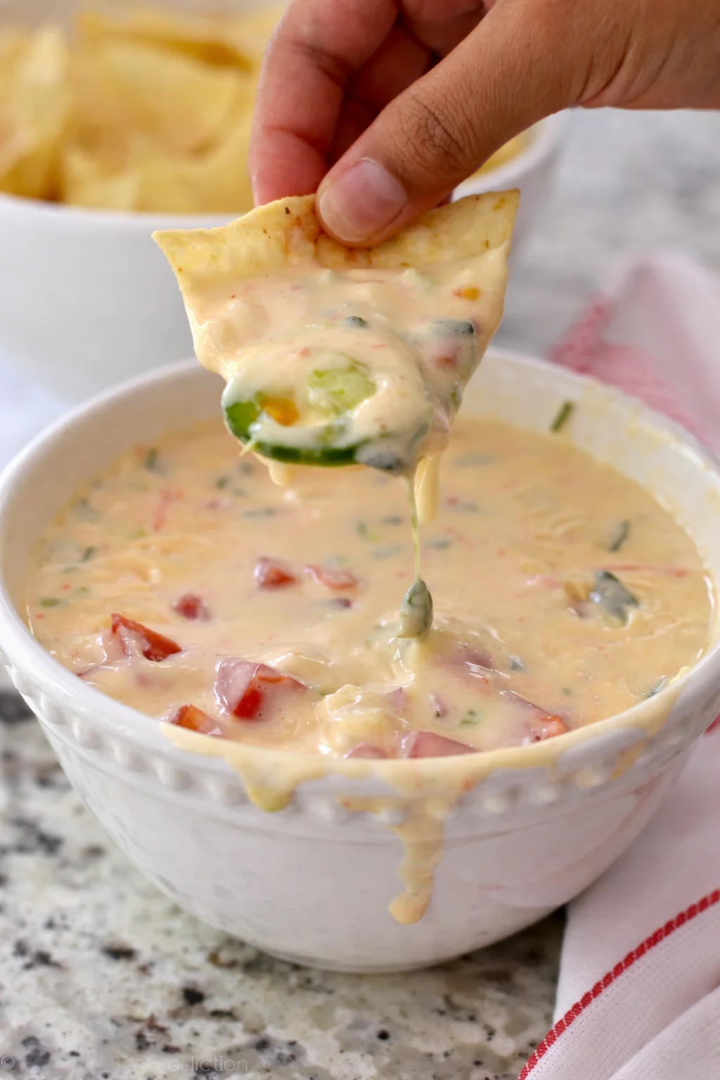 Smooth and creamy queso dip served in a bowl with tortilla chips
