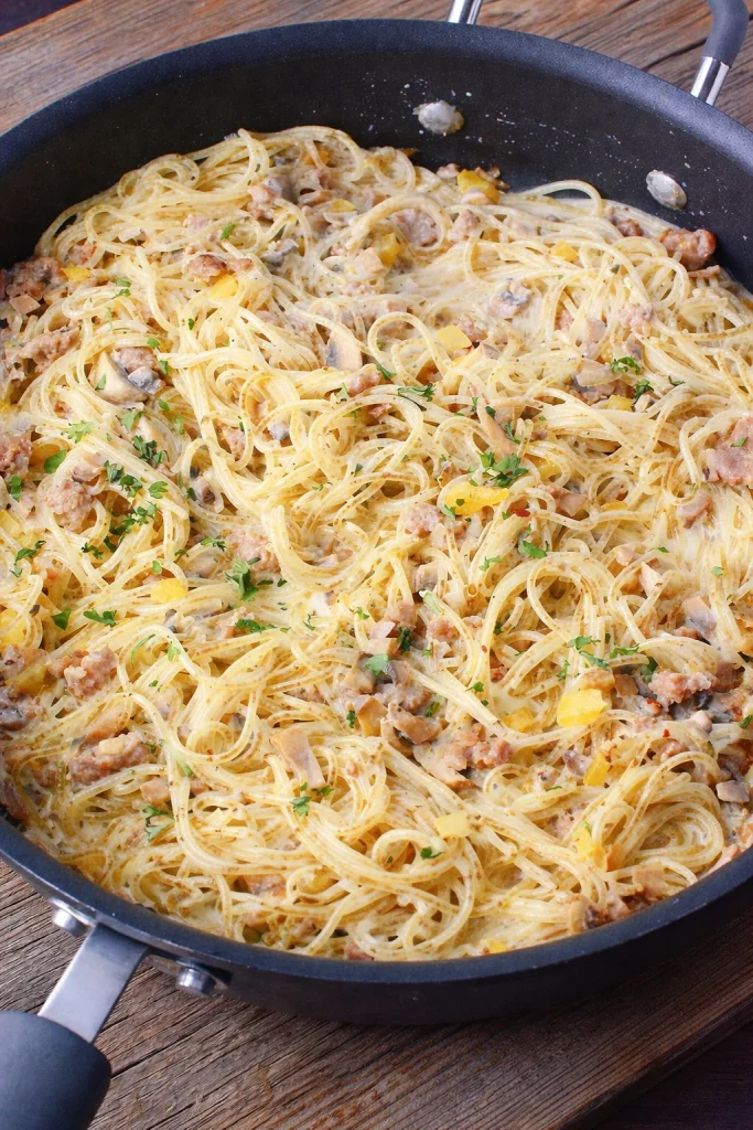 A bowl of creamy Sausage Boursin Pasta topped with herbs and sausage slices