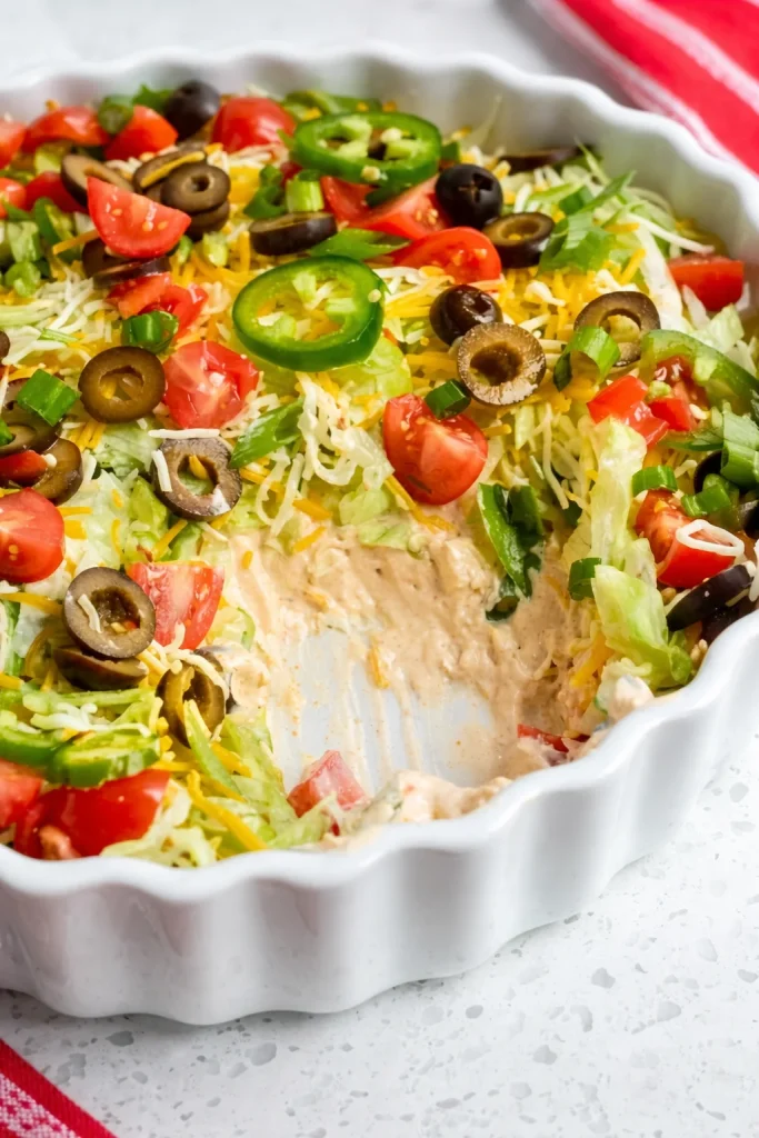 This incredibly scrumptious and easy Taco Dip Recipe with a sour cream and cream cheese base comes together in less than ten minutes, complete with all your favorite toppings.