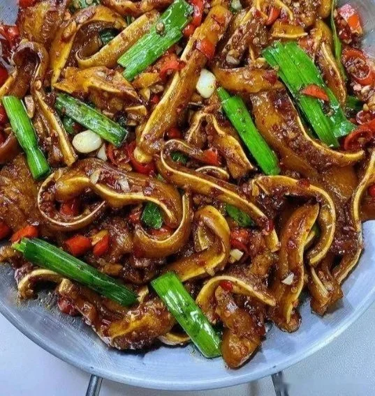 Plate of spicy stir-fried pig ears garnished with herbs and spices