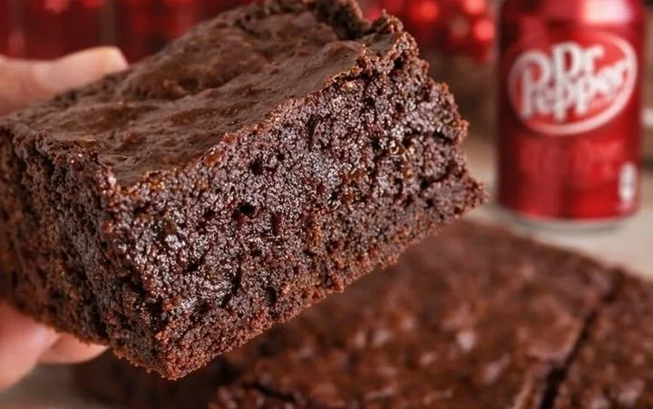 Delicious Dr Pepper fudge brownies served on a plate with chocolate drizzle.