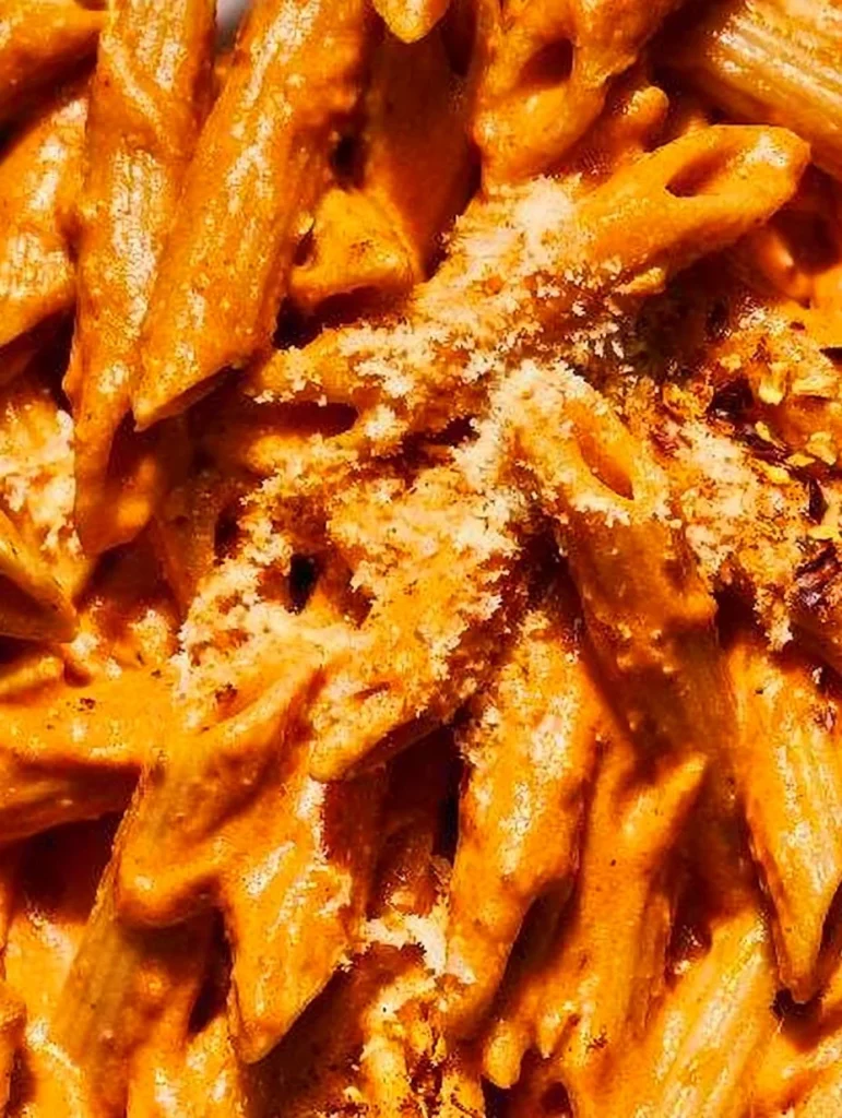 Plate of pasta with vodka sauce garnished with basil and Parmesan cheese
