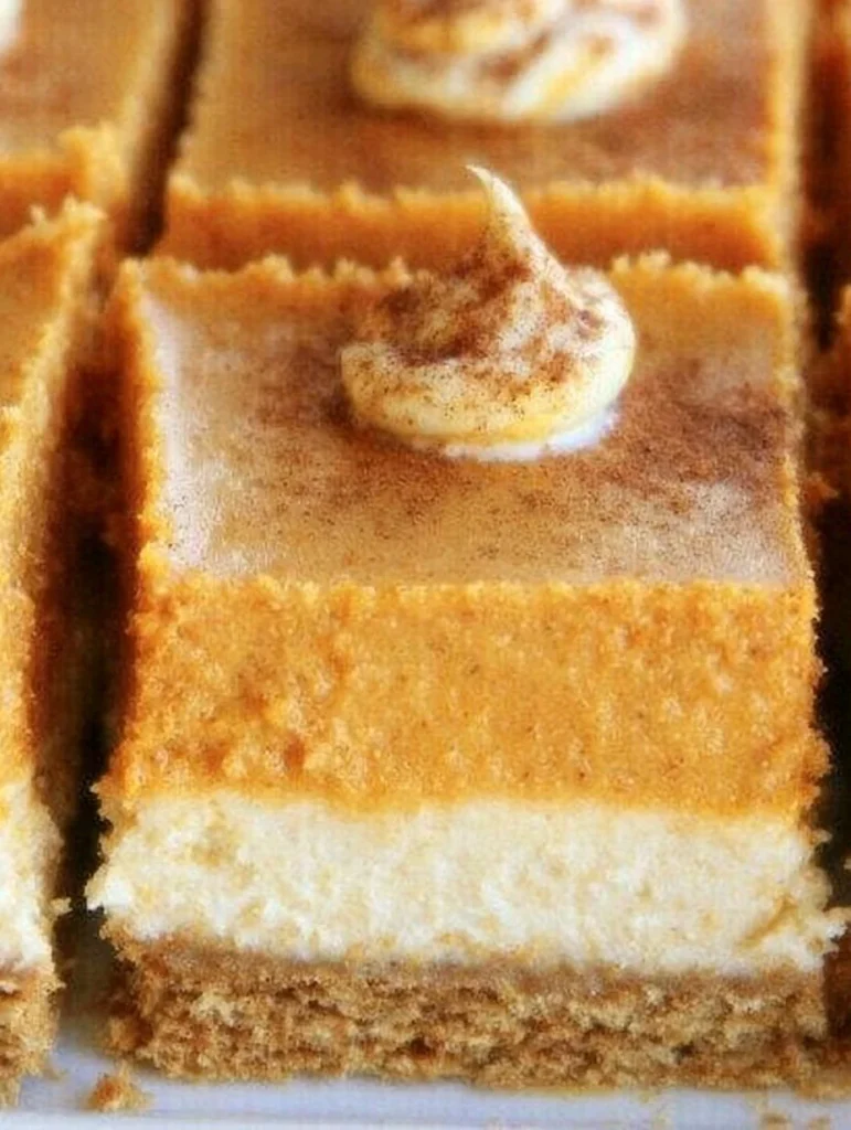 Delicious homemade pumpkin cheesecake bars topped with whipped cream.